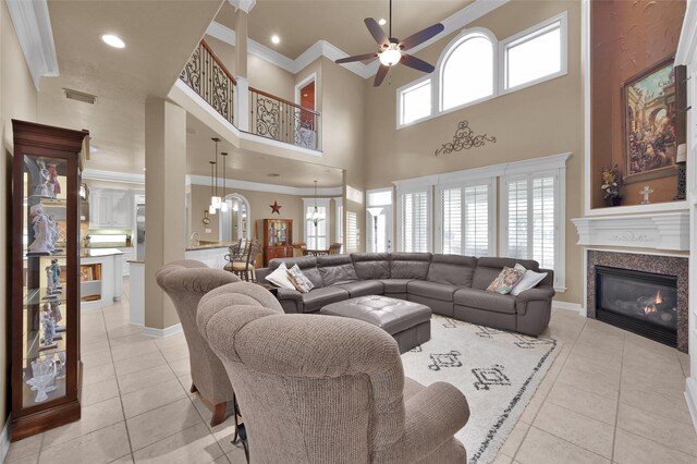 living room featuring light tile patterned flooring, a glass covered fireplace, visible vents, and ornamental molding