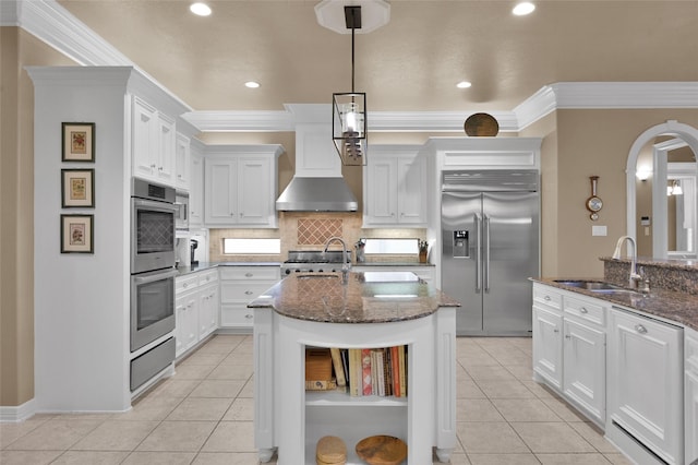 kitchen with light tile patterned flooring, stainless steel appliances, wall chimney exhaust hood, and a sink