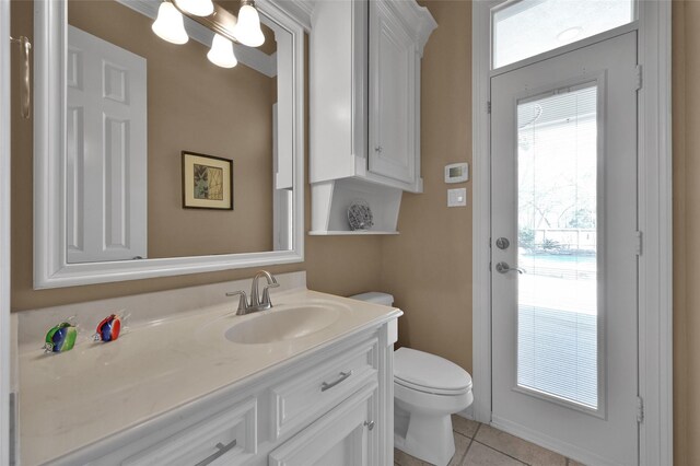 half bath with toilet, vanity, and tile patterned flooring