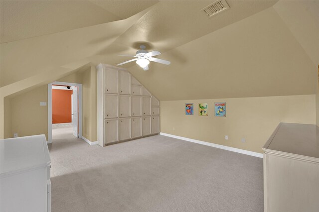 bonus room featuring visible vents, light carpet, lofted ceiling, a ceiling fan, and baseboards