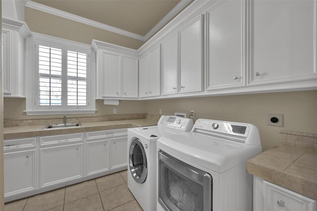 clothes washing area with crown molding, washer and clothes dryer, light tile patterned floors, cabinet space, and a sink