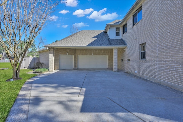 view of home's exterior featuring an attached garage, fence, brick siding, and roof with shingles