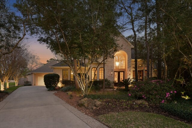 view of front of property featuring brick siding, french doors, driveway, and a garage