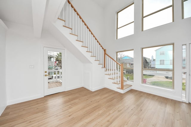 foyer entrance with a wealth of natural light, stairway, a high ceiling, and wood finished floors