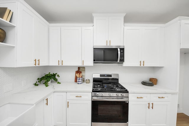 kitchen with open shelves, white cabinets, and appliances with stainless steel finishes