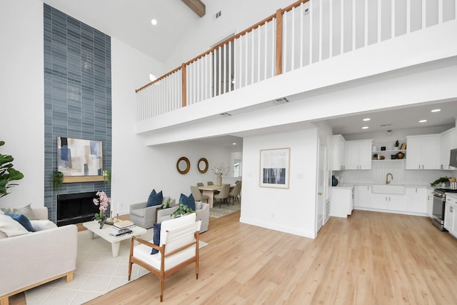 living area featuring visible vents, recessed lighting, light wood-type flooring, and a towering ceiling