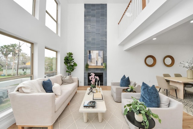 living area with a high ceiling, wood finished floors, and a tiled fireplace