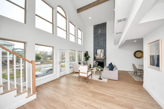 living area with stairway, beamed ceiling, visible vents, and light wood finished floors