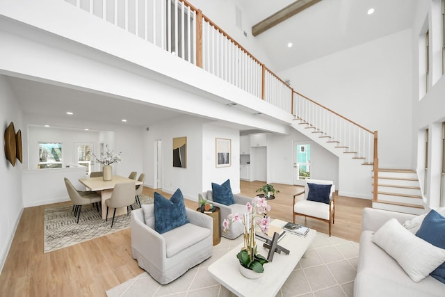 living room with a towering ceiling, recessed lighting, wood finished floors, and stairs