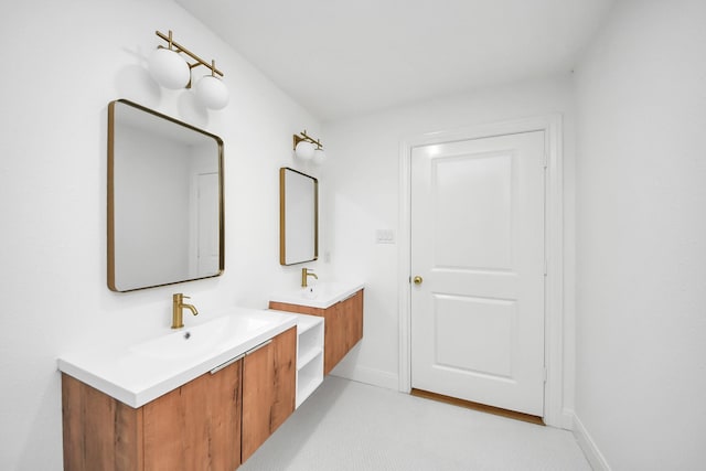 bathroom with two vanities, baseboards, and a sink