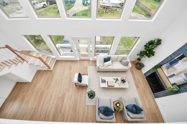 living area with wood finished floors, a skylight, and a towering ceiling