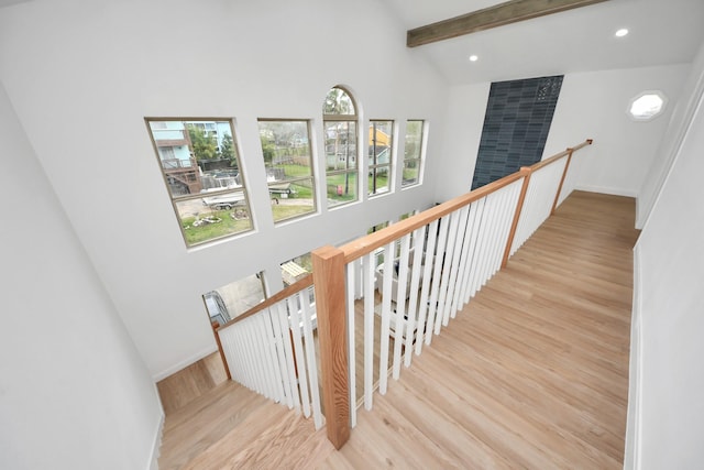 staircase with recessed lighting, lofted ceiling with beams, baseboards, and wood finished floors