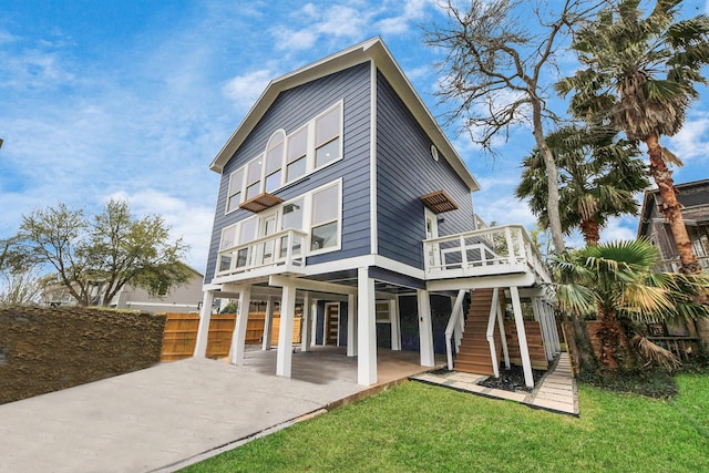 rear view of house featuring stairs, a deck, fence, and a lawn