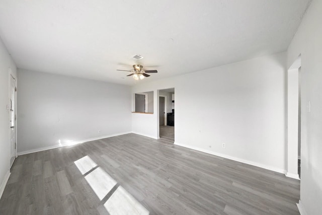 empty room with baseboards, wood finished floors, and a ceiling fan