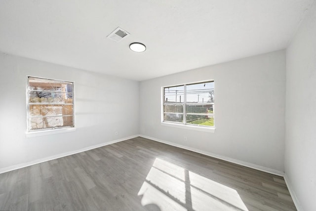 spare room with visible vents, baseboards, and wood finished floors