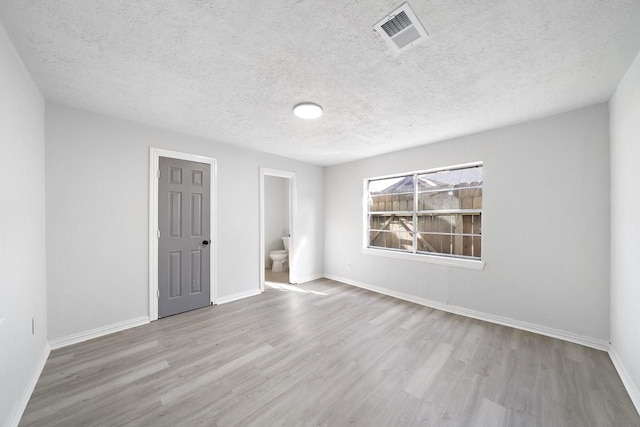 unfurnished room featuring visible vents, baseboards, a textured ceiling, and wood finished floors