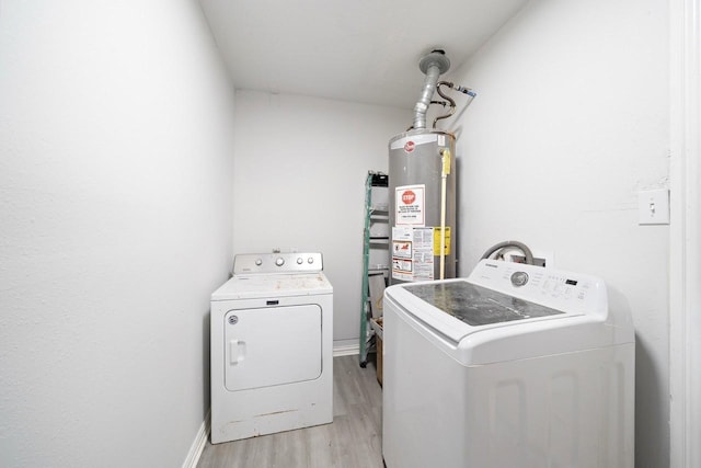 clothes washing area featuring baseboards, light wood-style flooring, water heater, and laundry area