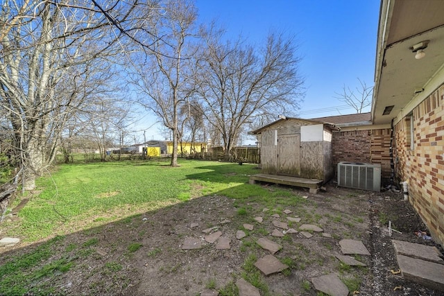 view of yard with an outbuilding, central air condition unit, a shed, and fence