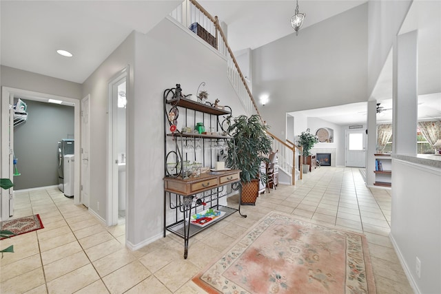 hallway featuring washer / clothes dryer, stairway, light tile patterned floors, and baseboards