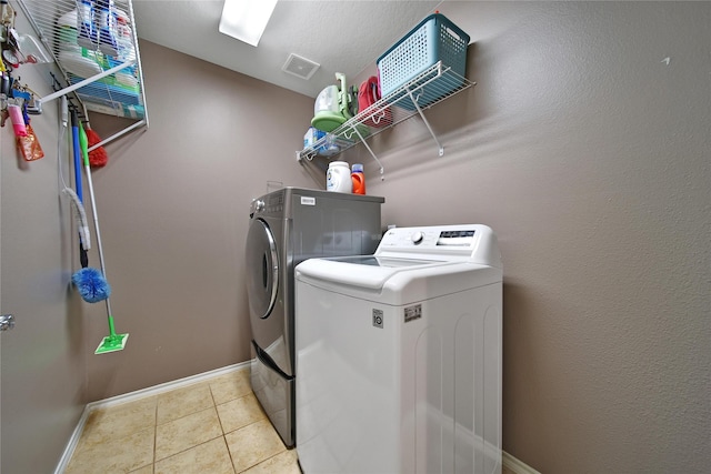 laundry area featuring tile patterned floors, visible vents, baseboards, laundry area, and washing machine and clothes dryer