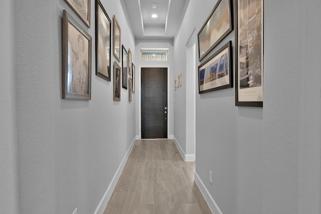 hall featuring baseboards and light wood finished floors