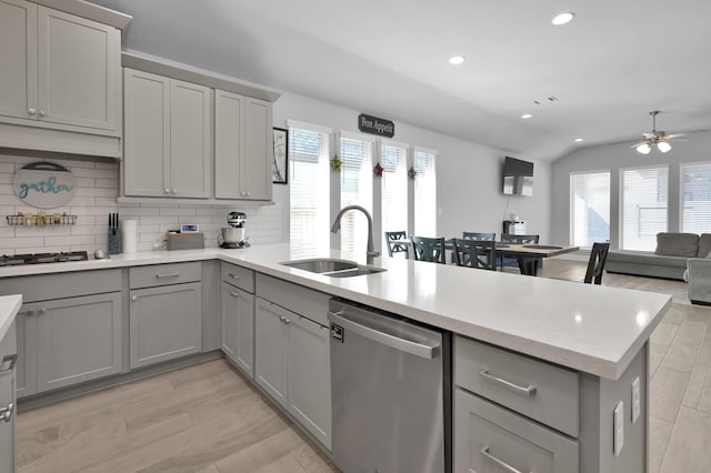 kitchen featuring a healthy amount of sunlight, a peninsula, gray cabinets, a sink, and appliances with stainless steel finishes