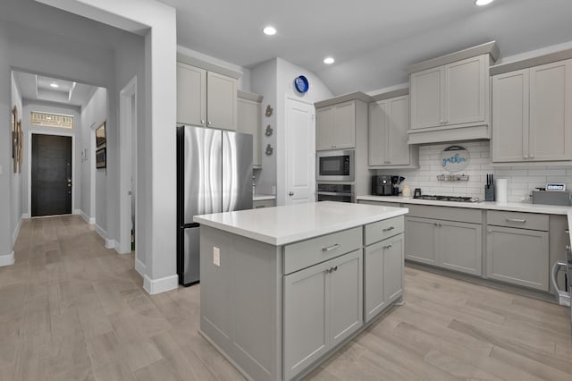 kitchen with stainless steel appliances, a kitchen island, decorative backsplash, and gray cabinets