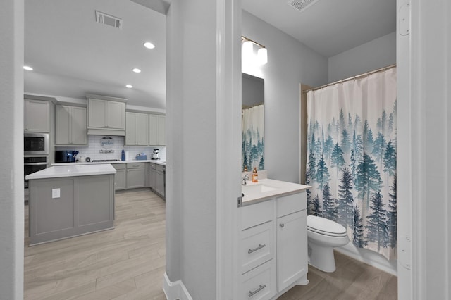 full bath with visible vents, toilet, backsplash, wood finished floors, and vanity