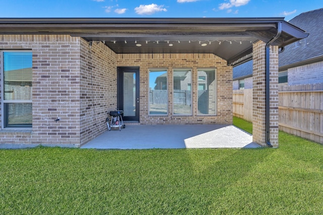 exterior space featuring brick siding, a yard, and fence