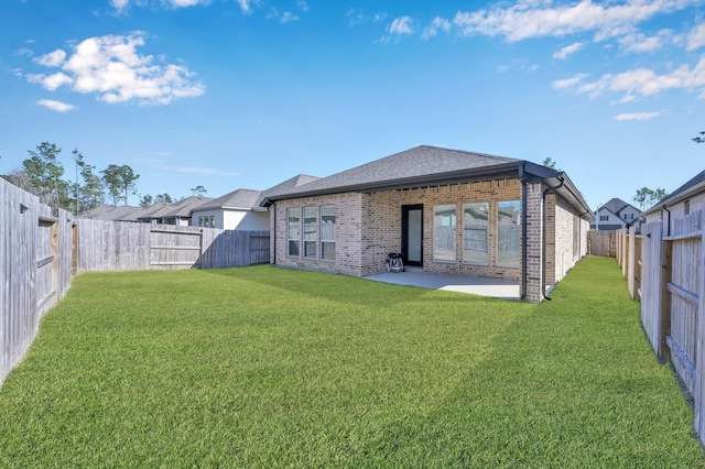 back of property featuring brick siding, a fenced backyard, a lawn, and a patio area