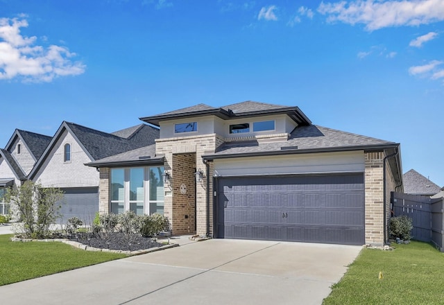 prairie-style home with fence, roof with shingles, concrete driveway, a front yard, and brick siding