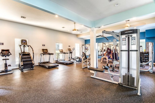 exercise room with visible vents, baseboards, a ceiling fan, and decorative columns