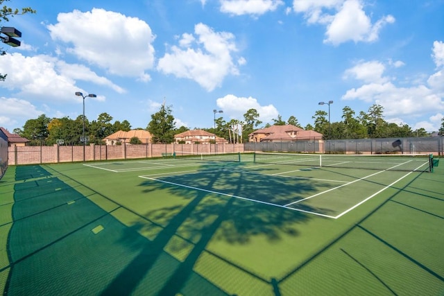 view of tennis court featuring community basketball court and fence