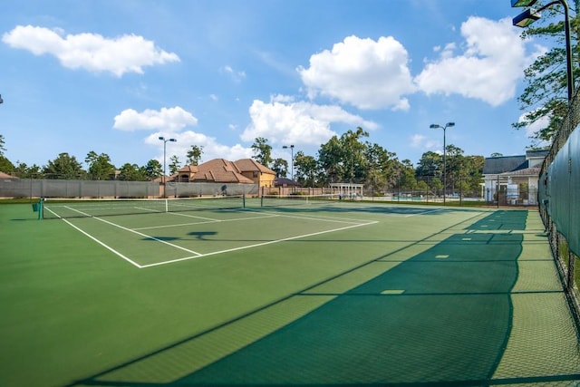 view of tennis court with community basketball court and fence