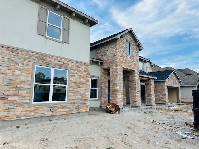 rear view of house featuring stucco siding and stone siding