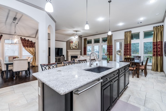 kitchen featuring a sink, plenty of natural light, a ceiling fan, dishwasher, and a fireplace
