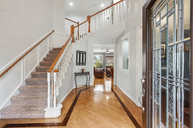 entryway with wood finished floors, a high ceiling, arched walkways, ornamental molding, and a decorative wall