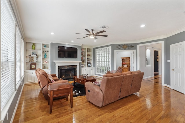 living room featuring visible vents, a stone fireplace, light wood-type flooring, and ornamental molding