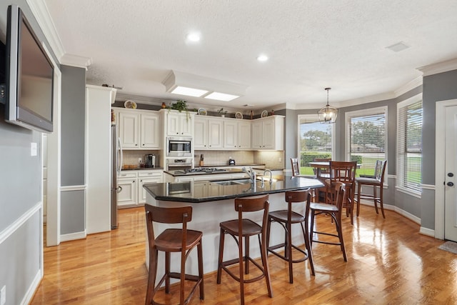 kitchen featuring decorative backsplash, a kitchen bar, light wood finished floors, and stainless steel appliances