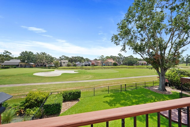 view of property's community featuring golf course view, a lawn, and fence