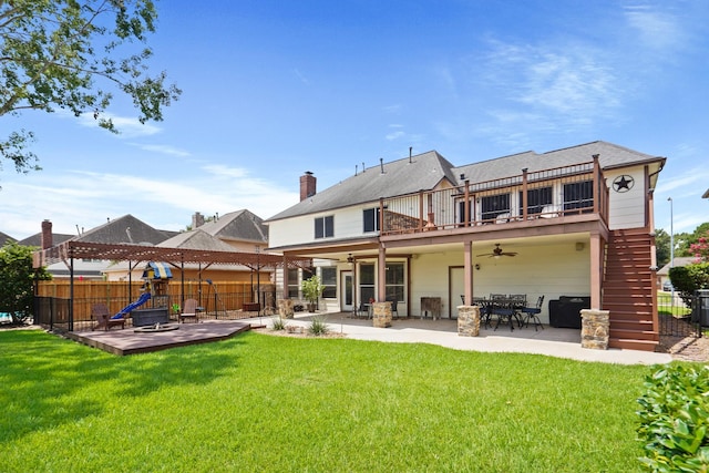 rear view of property featuring a ceiling fan, stairs, fence, and a lawn