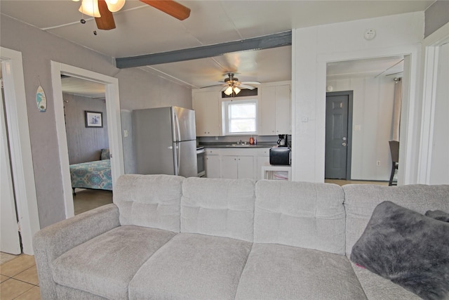 419 Murex St, Surfside Beach, TX 77541 - kitchen featuring dark countertops, light tile patterned floors, beam ceiling, freestanding refrigerator, and white cabinets
