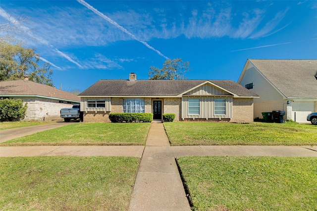 ranch-style home featuring board and batten siding, roof with shingles, a front yard, brick siding, and a chimney