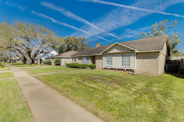 ranch-style house featuring a front yard, a chimney, board and batten siding, central air condition unit, and brick siding