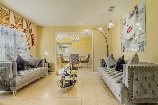 living area featuring visible vents, wallpapered walls, tile patterned flooring, an accent wall, and a notable chandelier