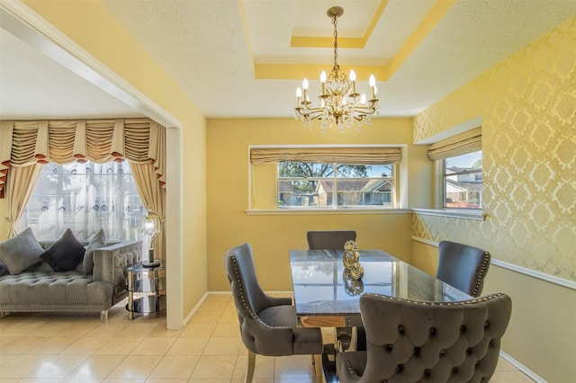 tiled dining room with baseboards, wallpapered walls, an inviting chandelier, a textured ceiling, and a raised ceiling