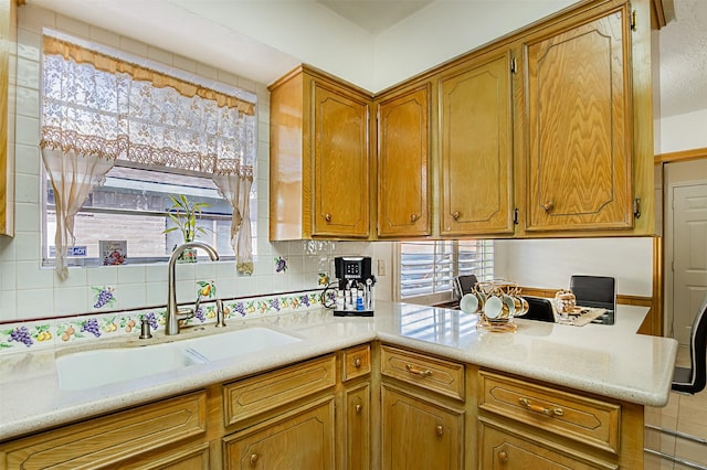 kitchen with a sink, tasteful backsplash, a peninsula, and a wealth of natural light