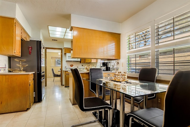 kitchen featuring brown cabinetry, light countertops, and freestanding refrigerator