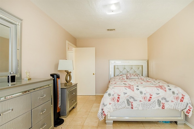 bedroom featuring light tile patterned floors, visible vents, and a textured ceiling