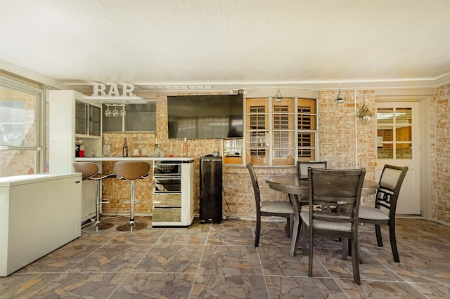 dining area featuring stone finish floor and brick wall